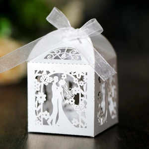 Detailed laser-cut wedding favor box with bride and groom silhouette and white silk ribbon