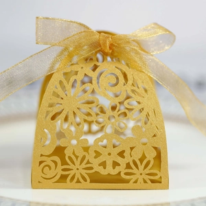 Detailed laser-cut gold favor box with floral patterns and matching ribbon bow