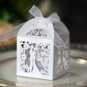 Detail of laser-cut hollow wedding favor box with bride and groom pattern and ribbon