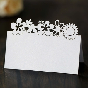 Macro view of white laser-cut sunflower place card with pearlescent finish on dark wood