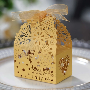 Close-up of golden laser-cut wedding favor box with floral patterns and gold ribbon bow