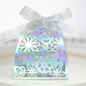 Iridescent laser-cut hollow floral candy box with a white ribbon bow on a ceramic plate