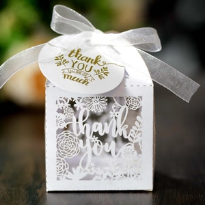 Macro detail of white laser-cut favor box with thank you tag and elegant ribbon tie