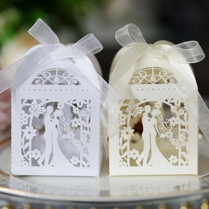 Close-up of laser-cut hollow wedding favor boxes with groom bride silhouette and ribbon