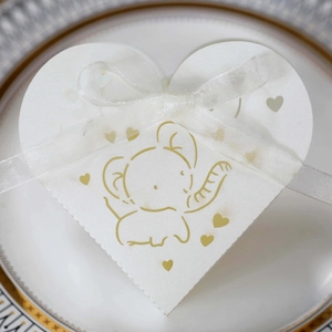Dettaglio della scatola di caramelle bianca a cuore con elefante dorato e nastro di seta