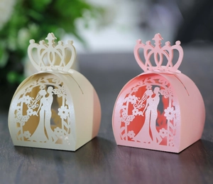 Detail of laser-cut crown wedding candy boxes with bride and groom silhouette patterns