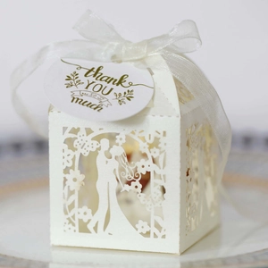 Close-up of laser-cut wedding favor box with ribbon bow and thank you tag