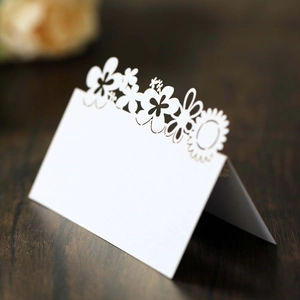 Macro detail of laser-cut sunflower floral design on elegant white wedding table cards