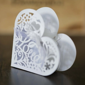 Laser-cut white heart-shaped wedding favor box with Love script and ribbon detail
