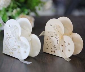 Dettaglio di scatole regalo a cuore con elefanti e nastri di seta su sfondo legno