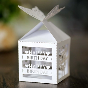White laser-cut Happy Birthday paper candy box with butterfly top on wooden table