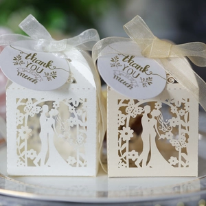 Detail of laser-cut wedding favor boxes with bride and groom silhouette and thank you tag