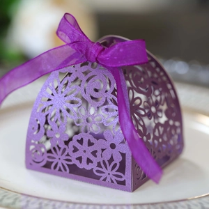 Detail of purple laser-cut wedding candy box with pearlescent finish and organza ribbon