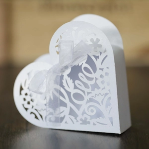 Close-up of laser-cut heart favor box with Love pattern and elegant white silk ribbon