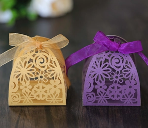 Detail of laser-cut floral patterns and silk ribbon on purple and gold wedding favor boxes
