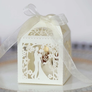Detail of white laser-cut wedding favor box with pearl paper and white organza ribbon