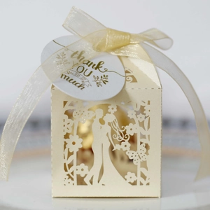 Detail of laser-cut wedding favor box with cream ribbon and Thank You gold tag