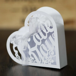 Close-up of white heart-shaped hollow gift box with Love You laser cut and silk ribbon