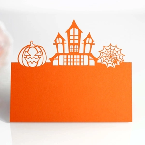 Laser-cut orange Halloween place card featuring a pumpkin castle and spider web detail