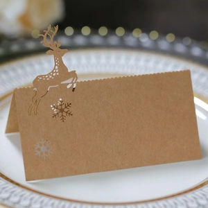 Detail of laser-cut reindeer and snowflake kraft paper place cards on a white dinner plate