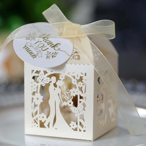 Detail of laser-cut wedding favor box with pearl paper and Thank You gold tag