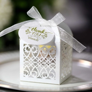 Close-up of laser-cut wedding favor box in white with silk ribbon and thank you tag