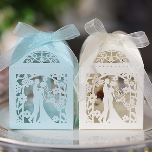 Close-up of laser-cut butterfly wedding favor boxes with ribbon on a ceramic plate