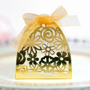 Detailed view of laser-cut gold wedding favor box with an elegant organza ribbon bow