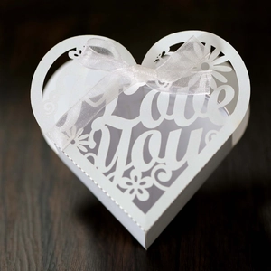 Macro shot of laser-cut heart candy box with Love You pattern and a white ribbon bow