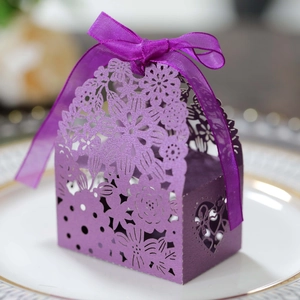 Close-up of purple laser-cut wedding favor box with pearl paper and silk ribbon