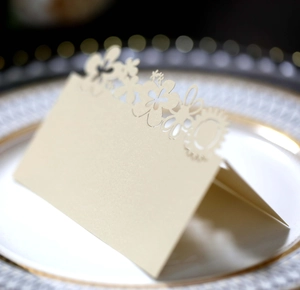 Macro detail of laser-cut butterfly floral patterns on a cream-colored wedding place card