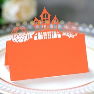 Laser-cut orange Halloween place card with pumpkin and castle on an elegant dinner plate