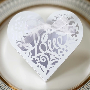 Close-up of white laser-cut heart favor box with Love engraving and ribbon bow
