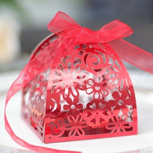 Macro detail of red laser-cut floral pattern and organza ribbon on wedding favor box
