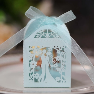 Close-up of light blue laser-cut candy box with elegant ribbon and couple silhouette