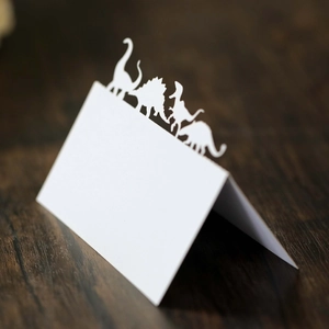 Marque-places dinosaures découpés au laser pour fête d'anniversaire sur table en bois