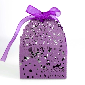 Detail of purple laser-cut flower patterns and chiffon ribbon on a wedding favor box