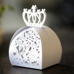 Detailed macro view of laser-cut white crown wedding favor box with pearl paper texture