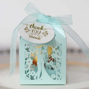 Close-up of light blue laser-cut wedding favor box with ribbon and thank you tag