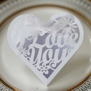 Detail of white heart-shaped hollow gift box with Love You text and silk ribbon