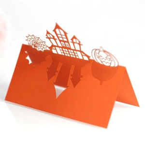 Detailed laser-cut hollow orange Halloween place card with castle, spider web, and pumpkin