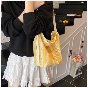 Détail du sac cabas en maille rayée jaune et blanc avec accents de bandoulière en cuir