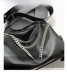 Close-up of black glossy oil wax leather shoulder bag with silver chunky metal chain strap
