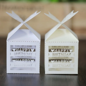Detailed laser-cut Happy Birthday gift boxes in white and beige on wooden table