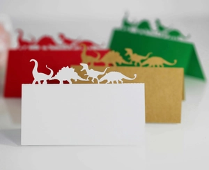 Marque-places dinosaures découpés au laser en papier blanc, vert et rouge pour décoration