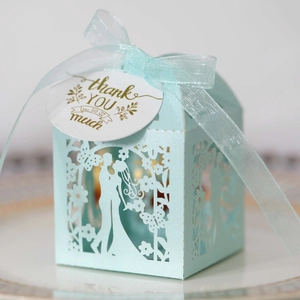Close-up of laser-cut light blue wedding favor box with ribbon and thank you tag