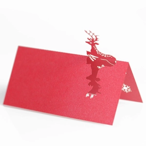 Detail of red laser-cut Christmas reindeer place card with delicate snowflake patterns