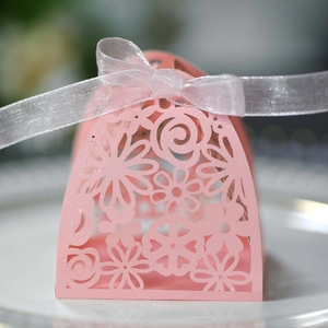 Close-up of pink laser-cut floral wedding favor box with a white organza ribbon bow