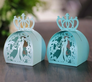 Detail of light blue laser-cut wedding candy box with crown top and couple silhouette