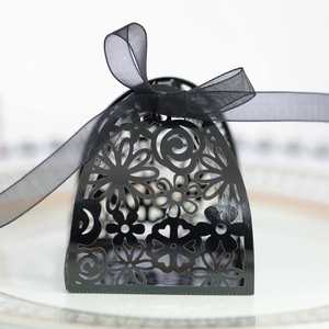 Close-up of laser-cut floral patterns on black gift box with a sheer organza ribbon bow